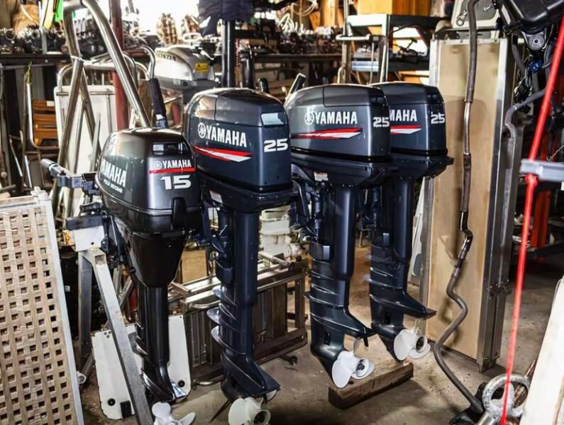 Close-up of a clean, silver used four-stroke outboard boat motor on a professional display stand in a marine shop.